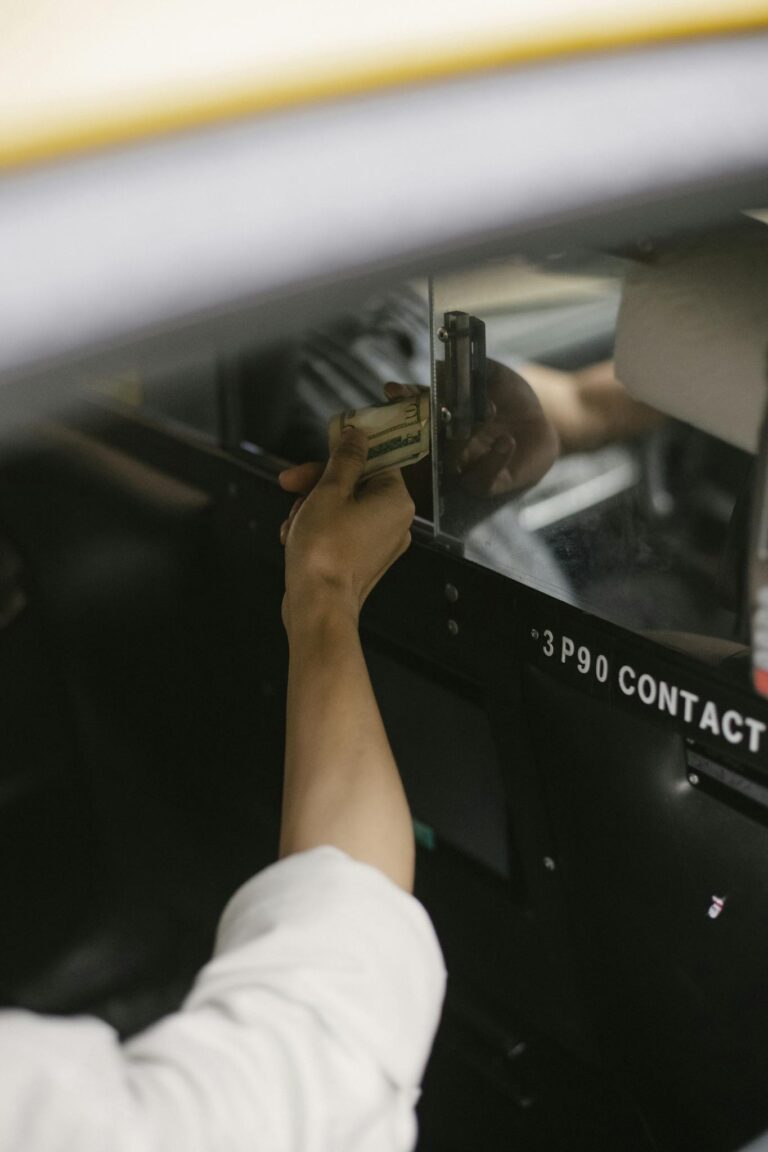 Crop faceless person sitting in cab and paying for transfer in modern city street